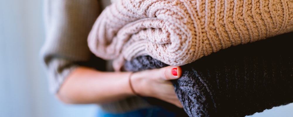 A woman holding clothing items.